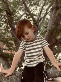 Low angle view of boy sitting on tree