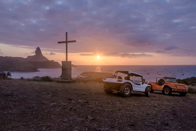 Cars on field against sky during sunset