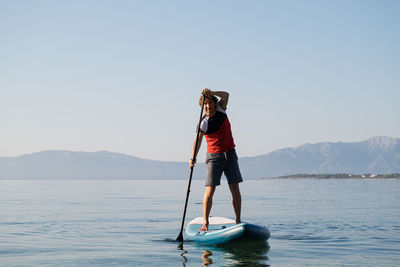 Man standing on boat in sea against clear sky