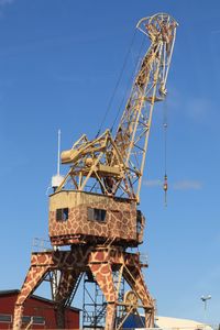 Low angle view of crane against clear blue sky