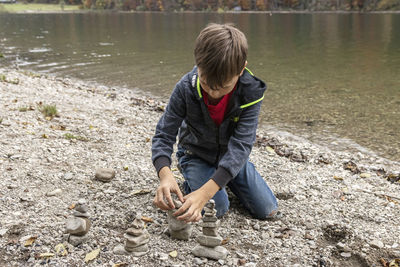 High angle view of boy stacking stones by lake