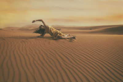 Woman in yellow dress playing with the wind in the desert iii