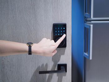 Close-up of woman hand using mobile phone against wall