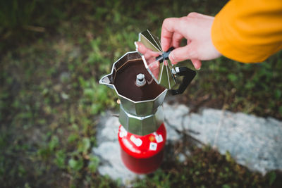 Cropped hand of woman making coffee outdoors