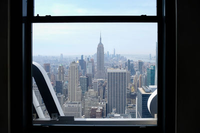 Modern buildings in city against sky seen through window