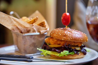 Close-up of tasty chicken burger with side of crispy fries in basket in restaurant