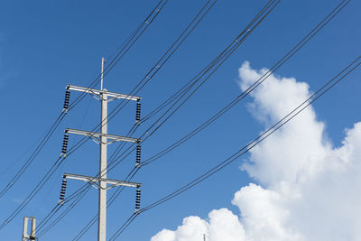 Low angle view of electricity pylon against blue sky