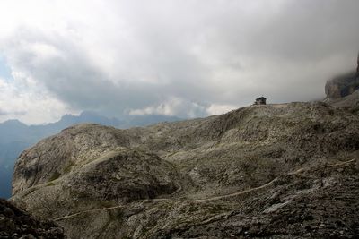 Low angle view of hut on mountain against cloudy sky