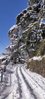 Snow covered road by mountain against sky