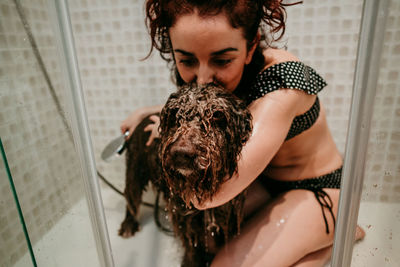Woman bathing dog in bathroom