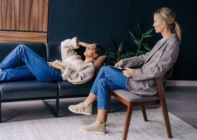 A psychoanalyst in a workshop listens to a woman lying on a couch and talking about her problems