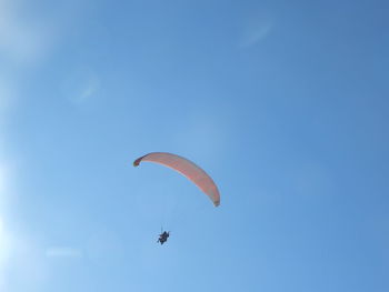 Low angle view of person paragliding against clear blue sky