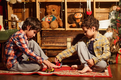 Portrait of smiling boys playing on the floor near the box in room with christmas decorations 