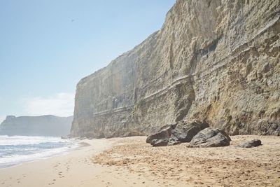 Rock formations on beach against sky