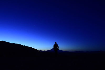 Silhouette man standing against blue sky at night