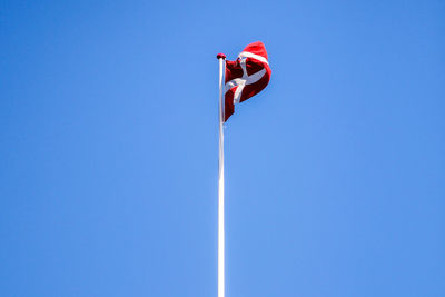 Low angle view of flag against clear blue sky