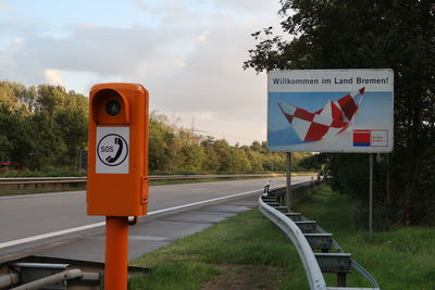 Information sign by road against sky