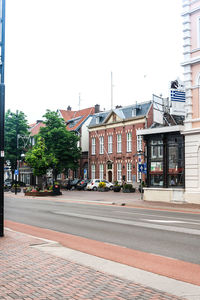 Road by buildings against clear sky