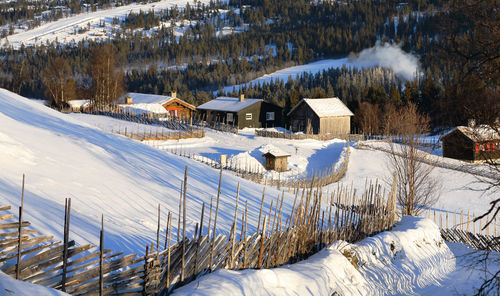 Houses on snow covered field against buildings