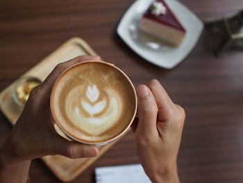 Midsection of woman holding coffee cup on table
