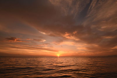 Scenic view of sea against dramatic sky during sunset