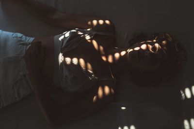 High angle view of woman lying on bed in darkroom