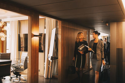 Female lawyers talking while walking in corridor at law office