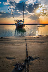 Sailboat in sea against sky during sunset