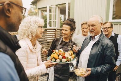 Smiling senior women and men enjoying garden party