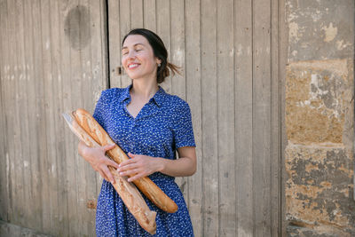 Young woman standing with french baguettes in the countryside