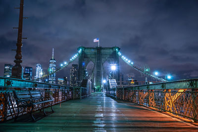 Illuminated bridge over river against sky at night