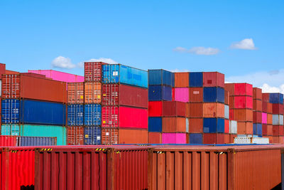 Stack of multi colored chairs on pier against sky