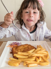 Portrait of girl having food at home