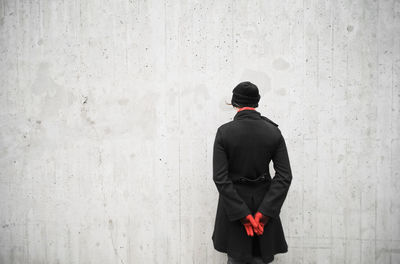 Rear view of woman walking against wall