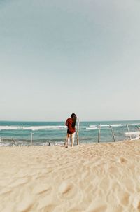 Rear view of friends on beach against sky