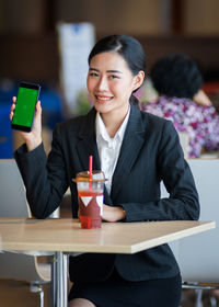 Portrait of a smiling young woman sitting at table