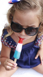 Toddler girl with blue swimsuit eating a popsicle in red, white and blue colors