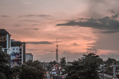 Trees and buildings against sky during sunset