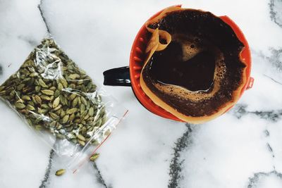 Directly above shot of coffee filter with cardamom on marble