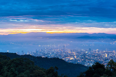 High angle view of silhouette cityscape against sky at sunset