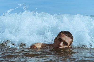 Young man swimming in splashing sea