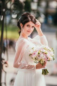 Portrait of young woman standing by flowering tree