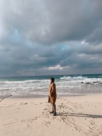 Full length of man standing on beach against sky