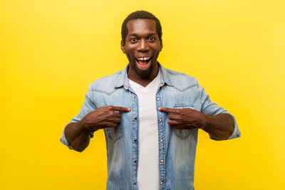 Portrait of smiling man standing against yellow background