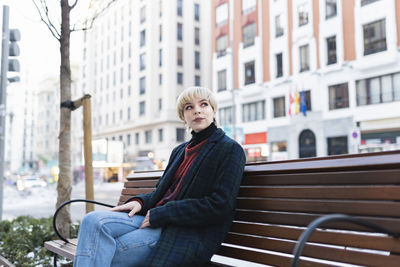 Man sitting on bench in city