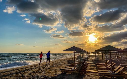 People on beach against sky during sunset