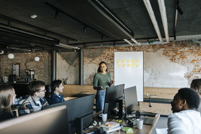 Female computer programmer explaining business strategies to colleagues in office