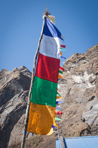 Low angle view of flag on mountain against clear sky