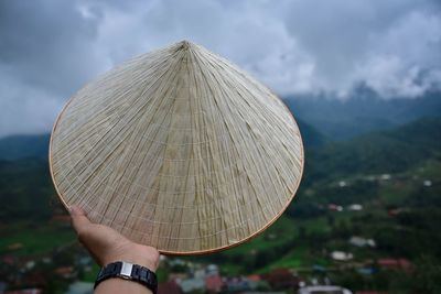 Cropped hand holding asian style conical hat