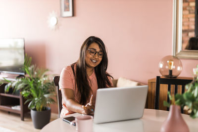 Portrait of young woman using phone while sitting on table